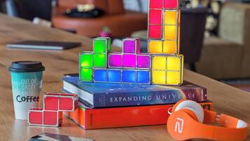 Une table sur laquelle se trouvent un Rubik’s Cube, une tasse de café, un livre intitulé « L’univers en expansion » et une paire d’écouteurs.