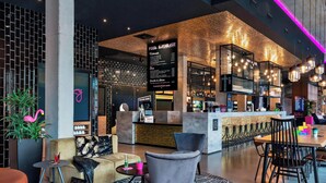 A modern bar area with a menu board, seating, and a bar counter. - Moxy Darmstadt (Darmstadt)