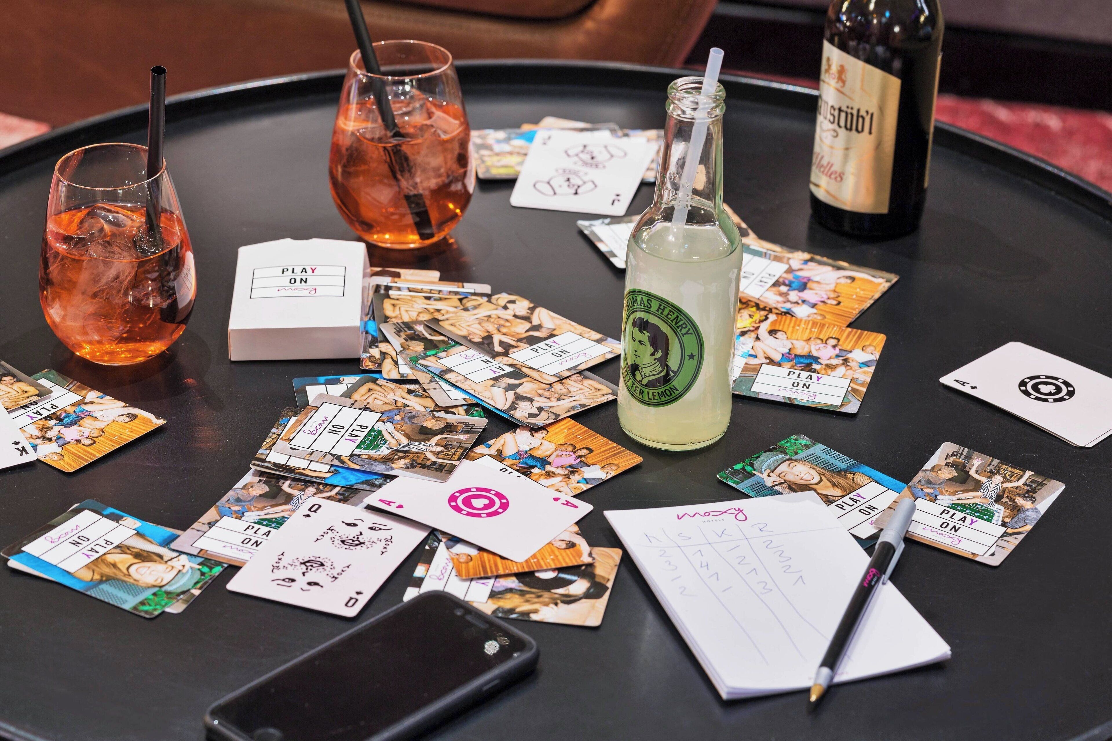 Una mesa con cartas, un teléfono inteligente, un cuaderno, un bolígrafo y dos vasos de una bebida.