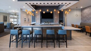 Eine moderne Bar mit einer zentralen Barinsel, Barhocker, hängenden Pendelleuchten und einem Flachbildfernseher.