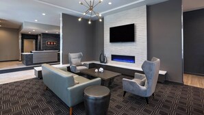 A modern living room with a fireplace, a mounted TV, and a contemporary chandelier.