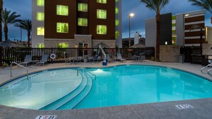 A hotel with a swimming pool, palm trees, and a modern building with illuminated windows. - TownePlace Suites By Marriott Las Vegas Stadium District (Las Vegas)