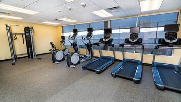Ein Fitnessstudio mit Laufbändern, Crosstrainern und einer Gewichtheberstation.