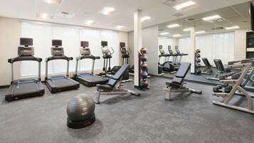 A gym with treadmills, elliptical machines, and free weights.