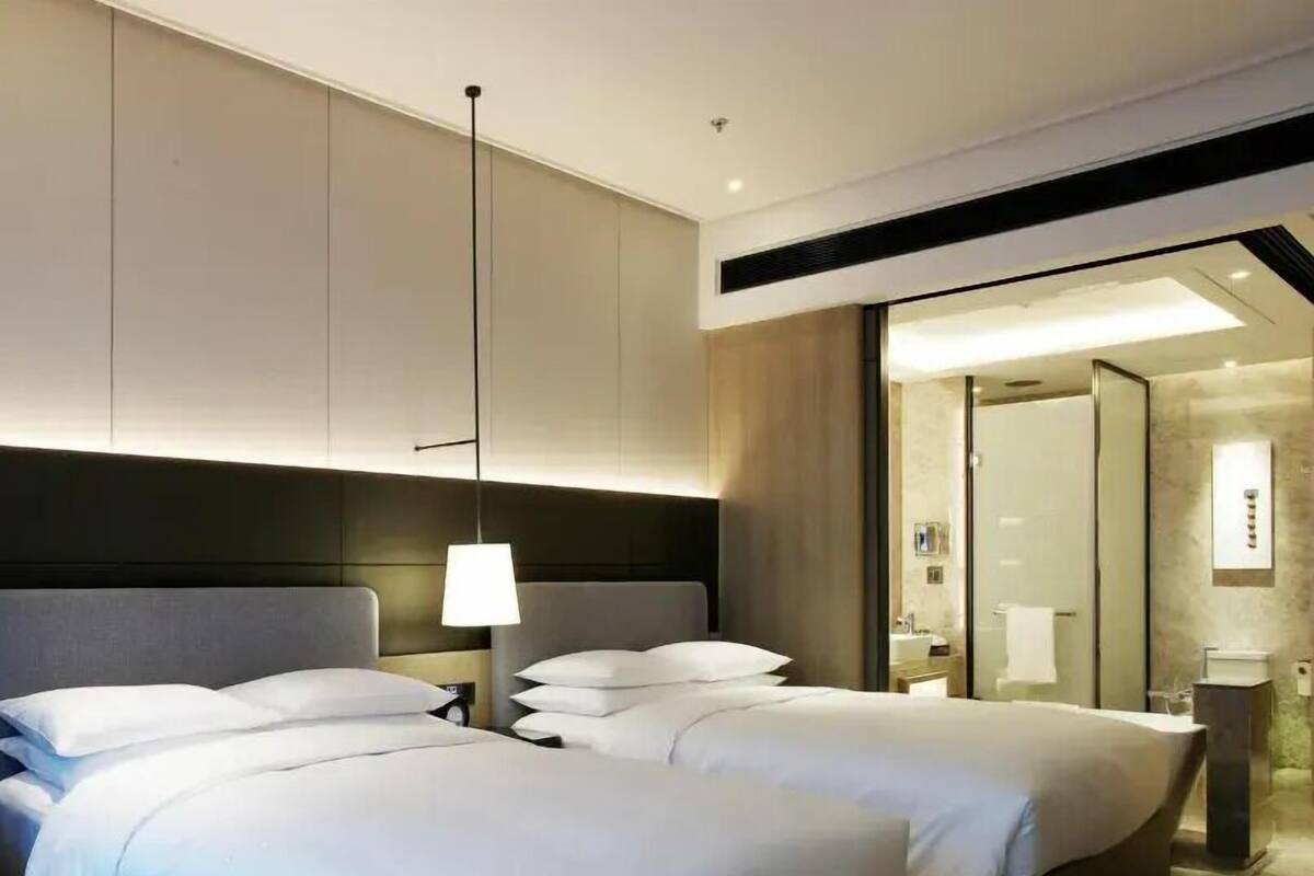 A hotel room with two beds, a large mirror, and a modern design.