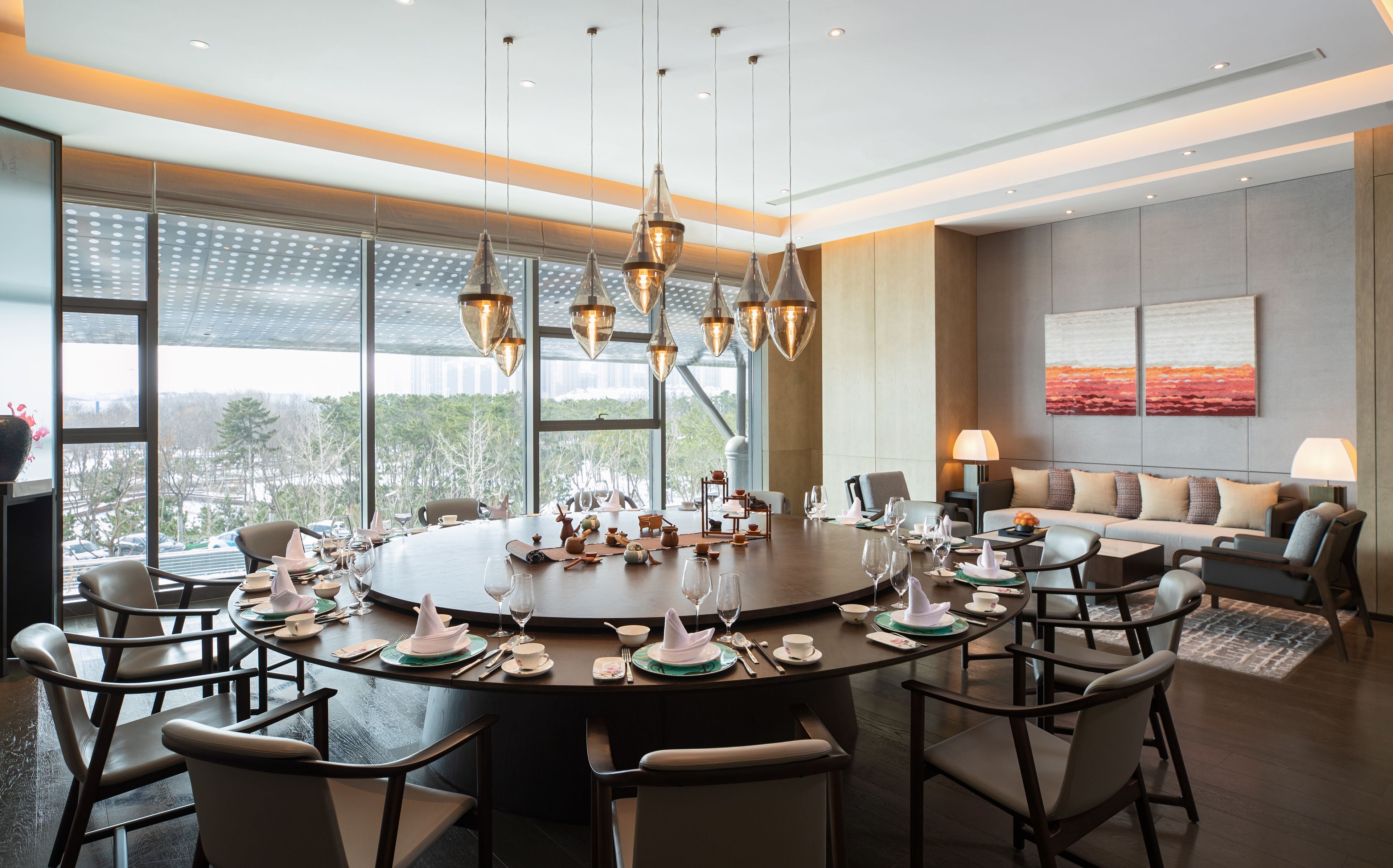A modern dining area with a round table set for a meal, surrounded by chairs.