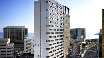 Un hotel de gran altura con varios pisos, un letrero llamativo y vistas a la ciudad y al océano.