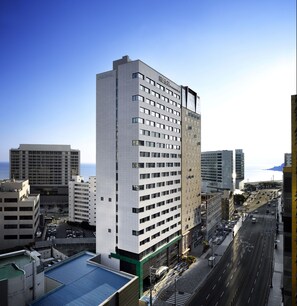 A high-rise hotel with multiple floors, a prominent sign, and a view of the cityscape and ocean.