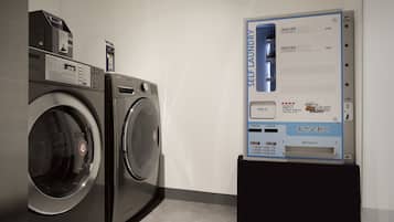 Een zelfbedieningswasserette met twee wasmachines en een informatiebord met instructies.