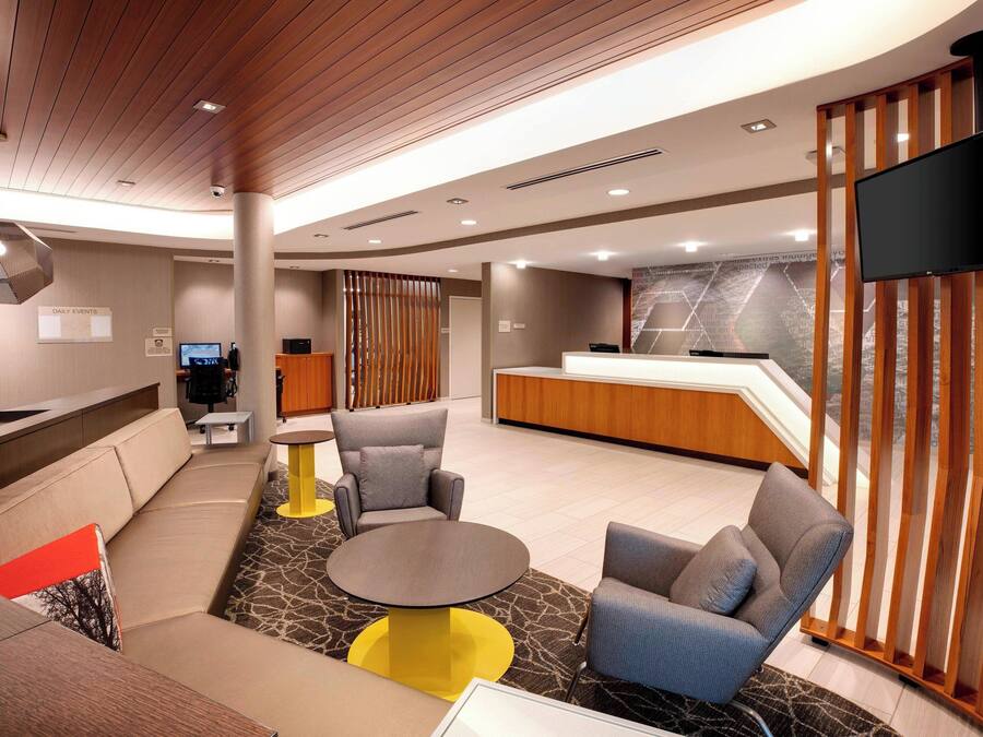 A modern lobby with a reception desk, seating area, and a large flat-screen TV mounted on the wall.
