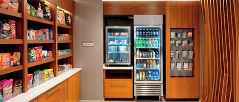 A well-stocked snack and beverage vending area with multiple shelves and a refrigerator.