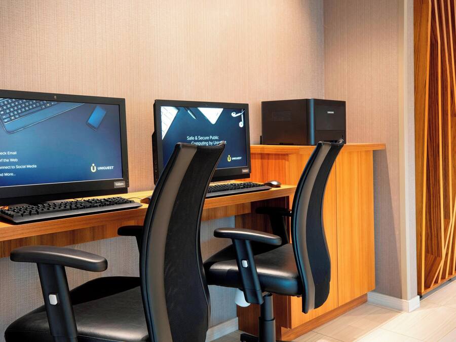 Un espacio de oficina moderno con dos escritorios, cada uno con una computadora y teclado.