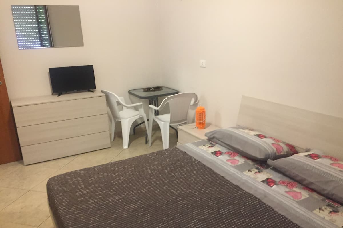 Une chambre à coucher comprenant un lit, un bureau, une chaise, une commode et un téléviseur.
