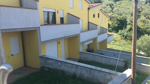 Un edificio amarillo de varios pisos con balcones y un pequeño patio.