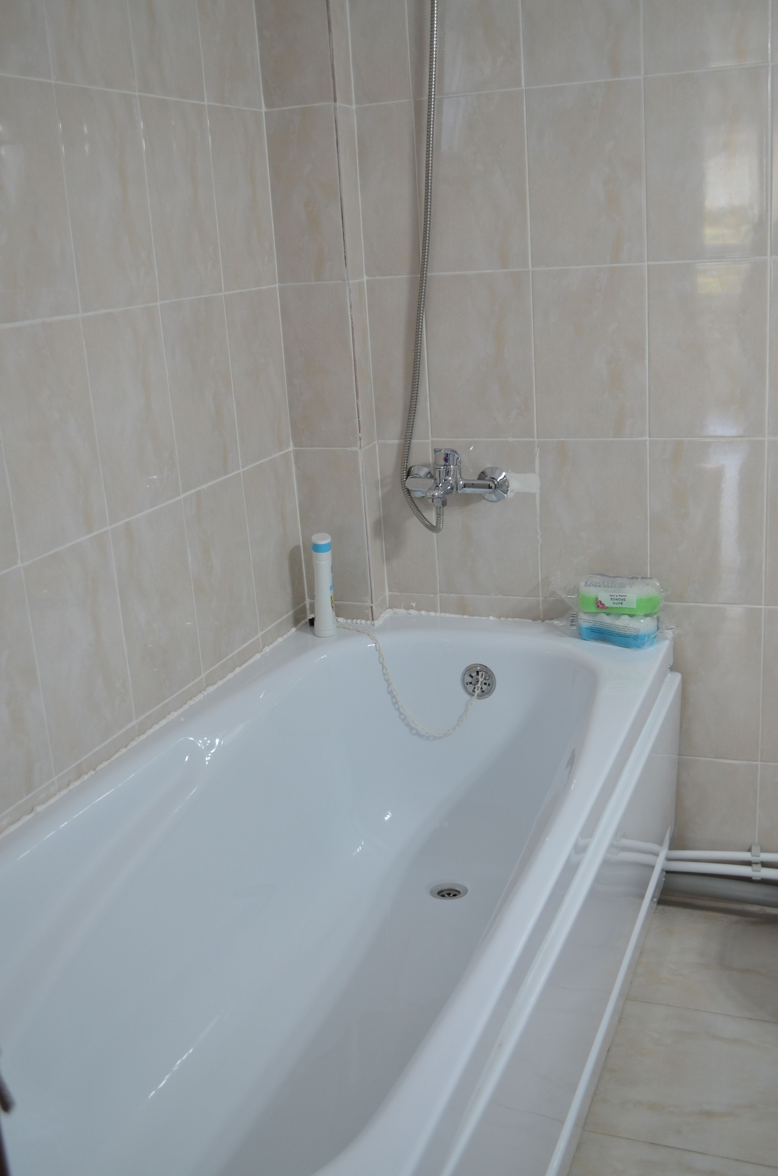 A bathroom with a bathtub, a shower head, and a toilet.