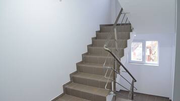 A staircase with a metal handrail and beige tiles.