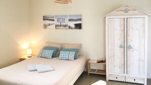 A bedroom with a bed, a wooden wardrobe, a wall-mounted shelf, and a hanging light fixture. - Estrella (Les Sables-d'Olonne)