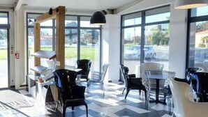 A modern interior with a glass display case, seating area, and large windows. - Estrella (Les Sables-d'Olonne)