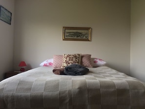 A neatly made bed with a patterned bedspread, several pillows, and a blanket. - Sæból Farm (Flateyri)