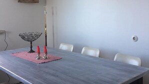 Une table à manger avec un set de table, des bougies et un bol décoratif. Des chaises blanches sont disposées autour de la table.