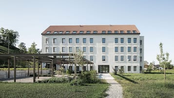 A modern building with a tiled roof, multiple windows, and a covered entrance area.