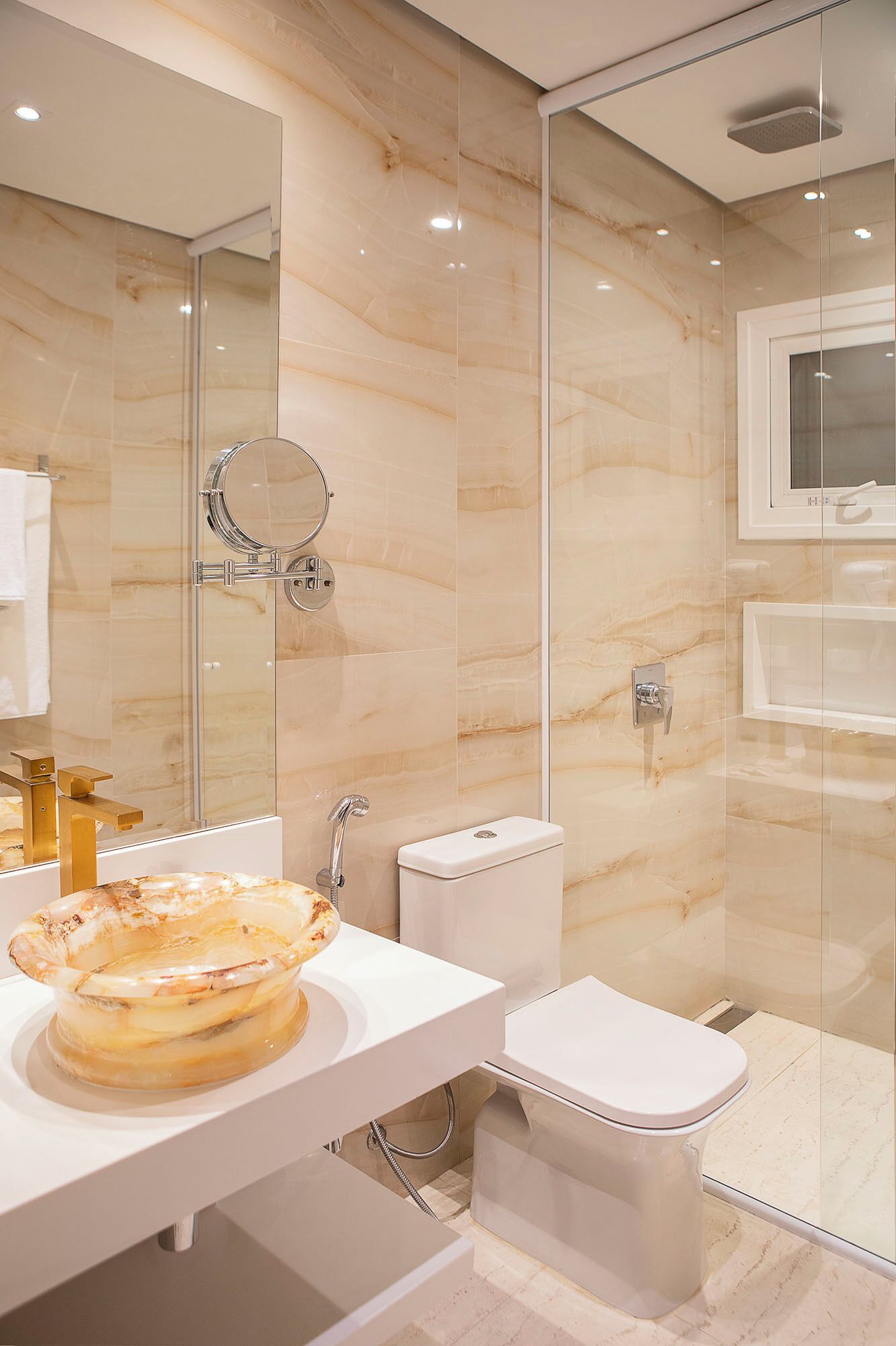 Uma casa de banho moderna com cabine de duche em vidro, lavatório branco com um recipiente decorativo e sanita.