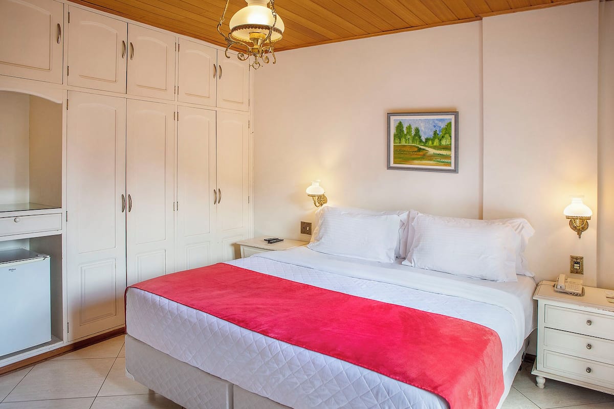 Un dormitorio con cama, paredes blancas, un cuadro y un armario.
