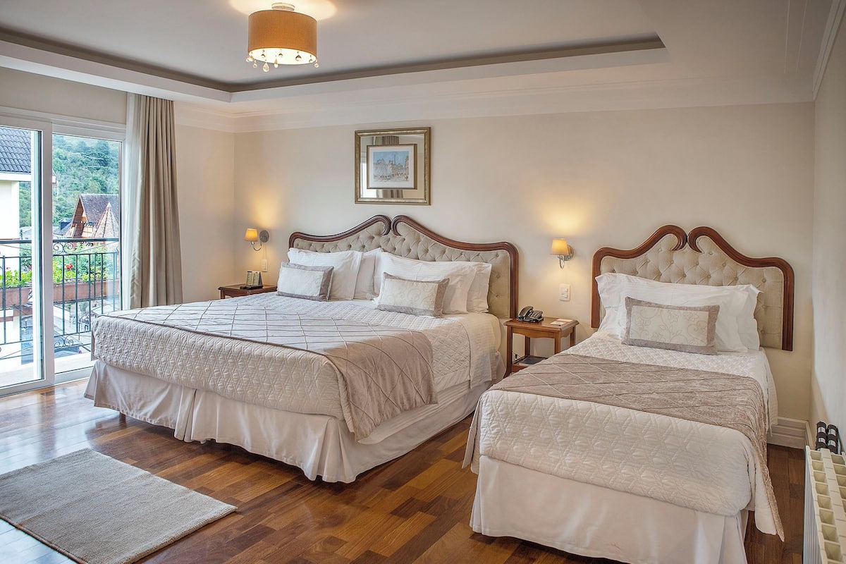Habitación de hotel con dos camas, balcón y vistas al exterior.