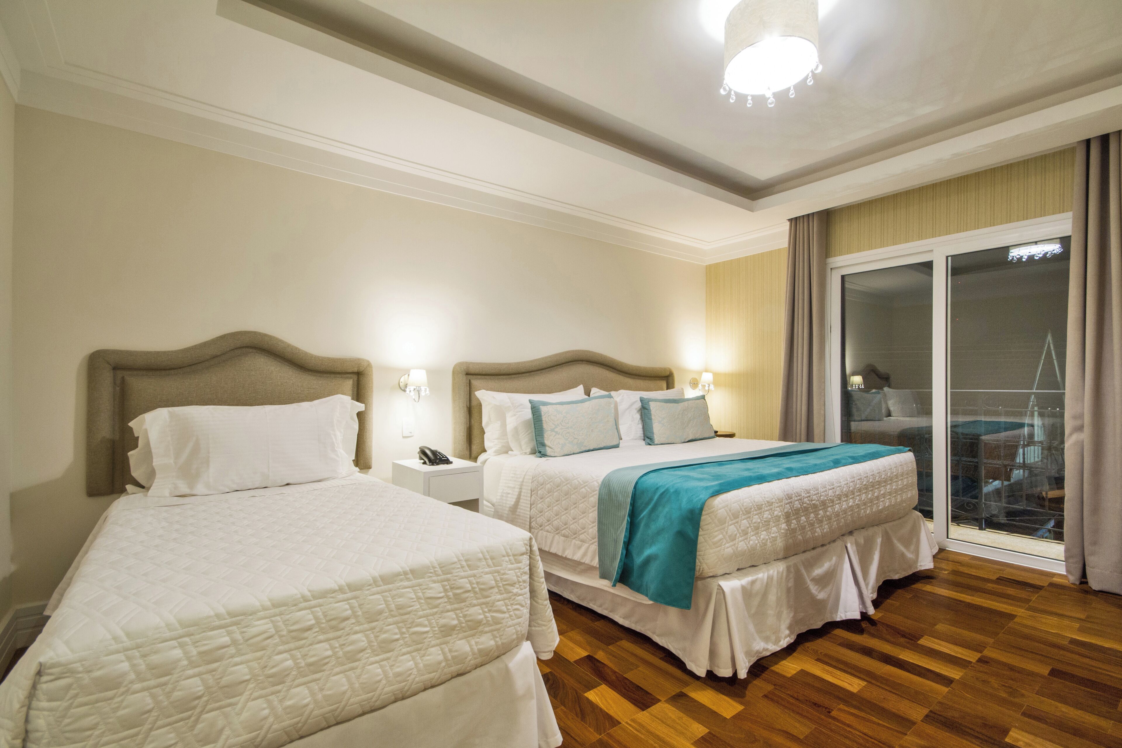 A hotel room with two beds, a large window with a view, and a wooden floor.