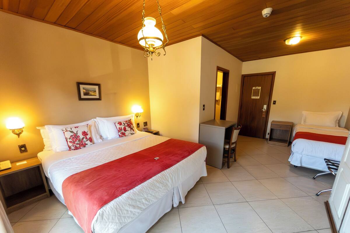 Habitación de hotel con una cama grande, un escritorio, una silla y una mesita.