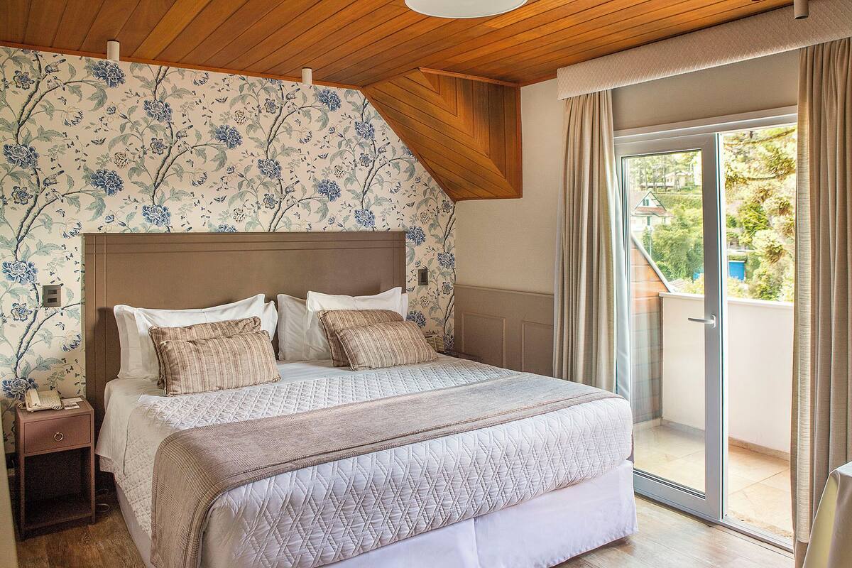 Un dormitorio con cama, mesita de noche y vistas al exterior.