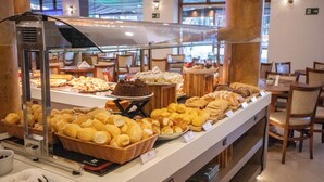 Mostrador de panadería con panes, pasteles y un pastel de chocolate.