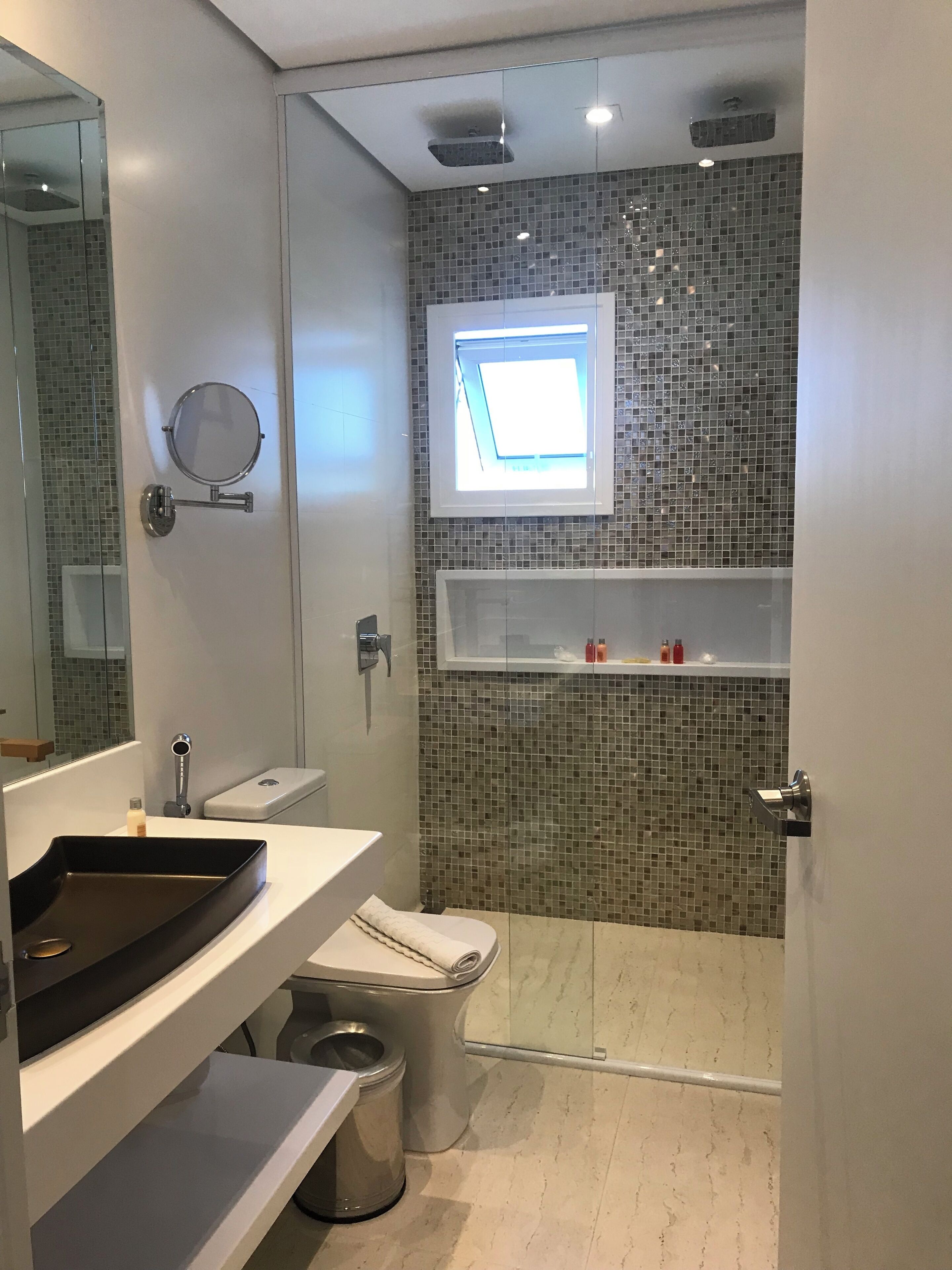 Un baño moderno con inodoro, bidé y una pequeña ventana.