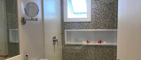 Un baño moderno con inodoro, bidé y una pequeña ventana.
