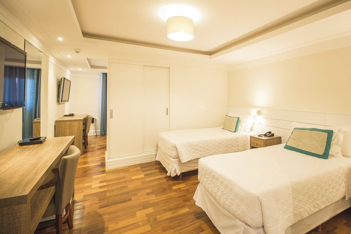 Habitación de hotel con dos camas, un escritorio y una silla.