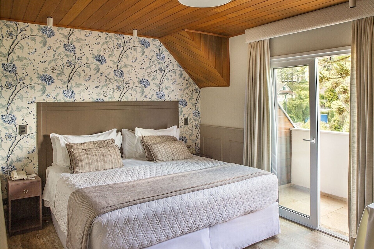 Un dormitorio con cama, mesita de noche y vistas al exterior.