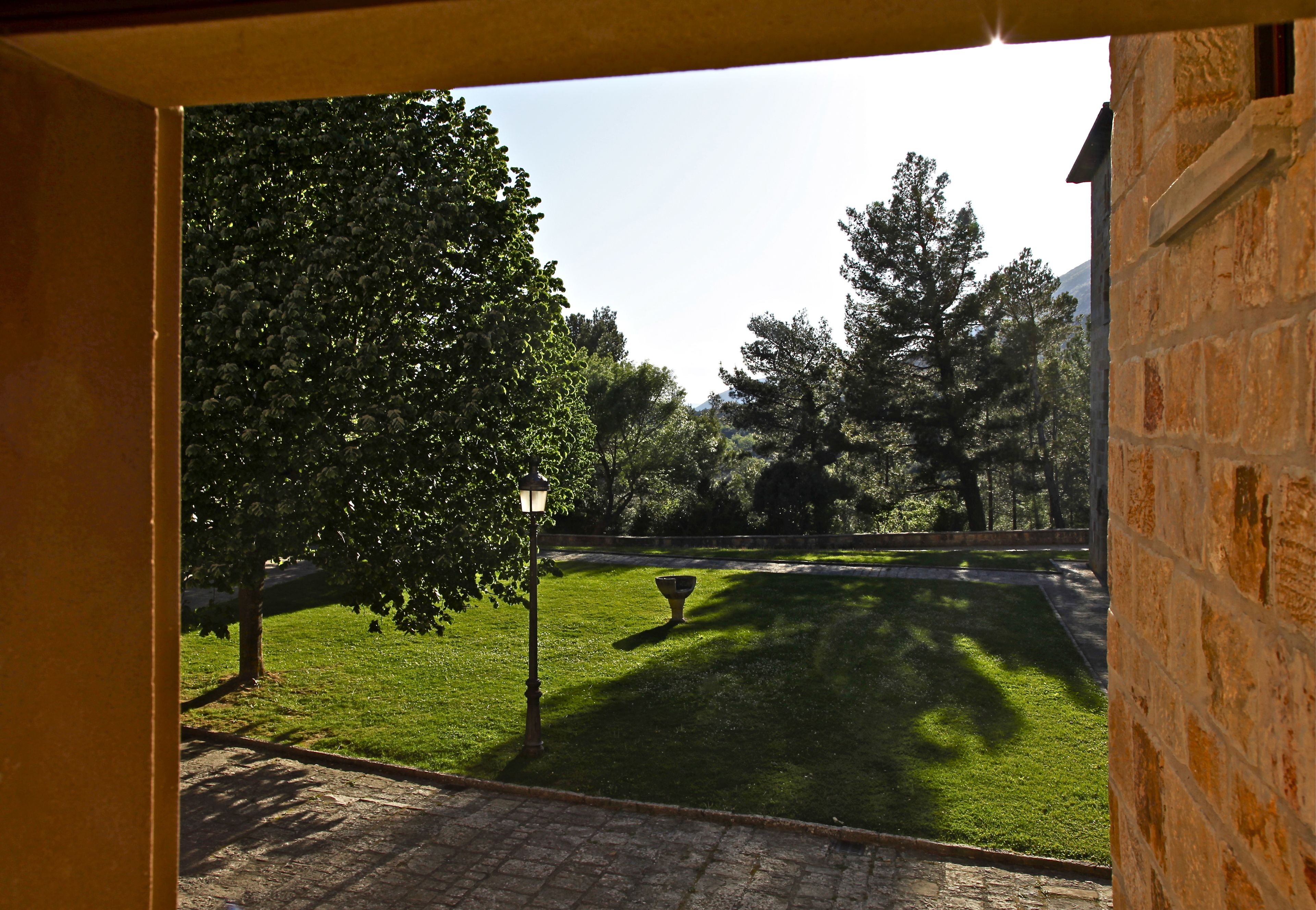 A courtyard with a paved pathway, a lawn, and a stone wall.