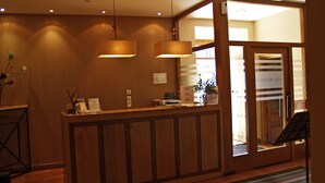 A reception desk with a wooden finish, a potted plant, and a sign indicating a restaurant and bar. - Hotel Monasterio de Leyre (Yesa)