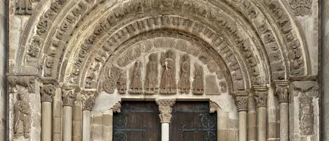 A detailed stone facade with a large arched doorway, flanked by columns and intricate carvings.