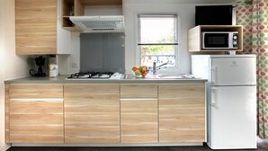 Une cuisine compacte équipée d’une cuisinière à gaz, d’un four à micro-ondes et d’un réfrigérateur.