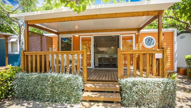 Une terrasse en bois avec une entrée couverte donnant sur un espace cuisine moderne.