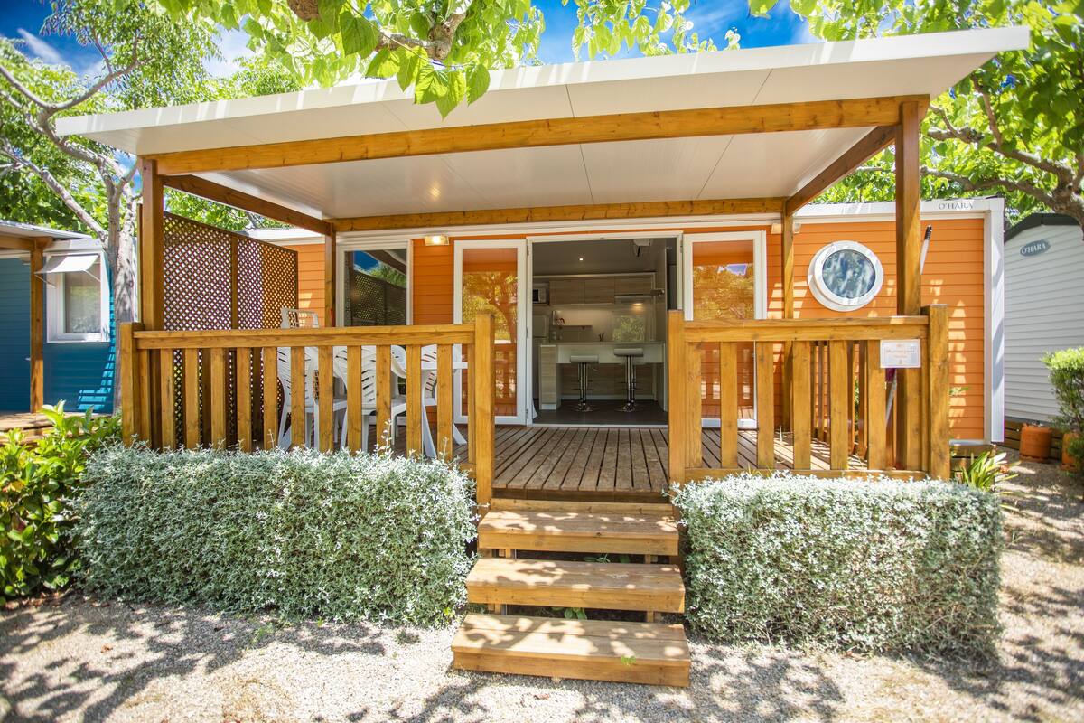 Una terraza de madera con un acceso cubierto que conduce a un área de cocina moderna.