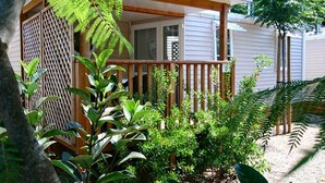 Une terrasse en bois dotée d’un espace abrité, entourée d’une végétation luxuriante et d’une clôture à treillis.