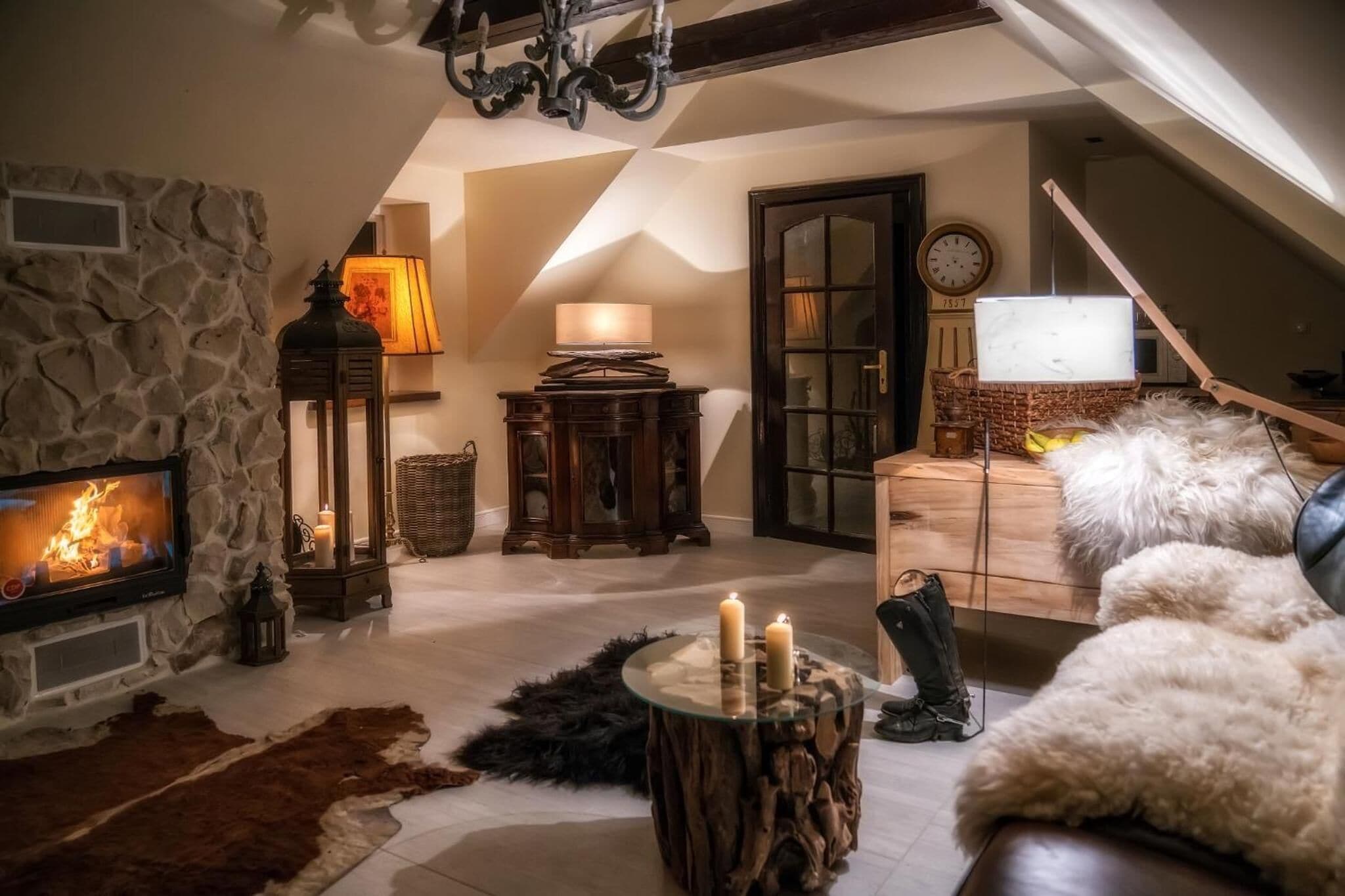 A cozy living room with a stone fireplace, a wooden coffee table with candles, and a leather sofa.
