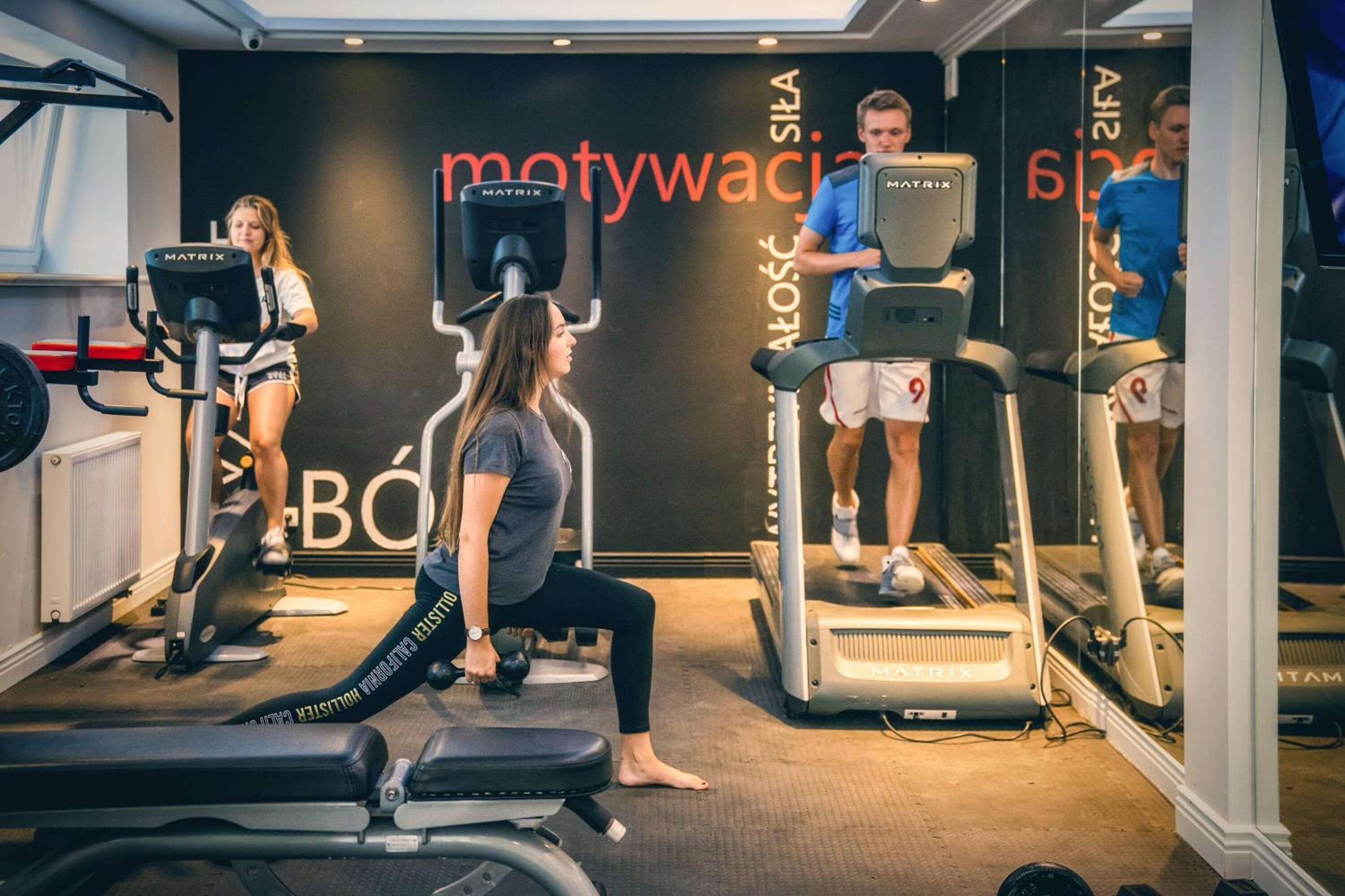 Un gimnasio con cintas de correr, una bicicleta estática y un banco de pesas.
