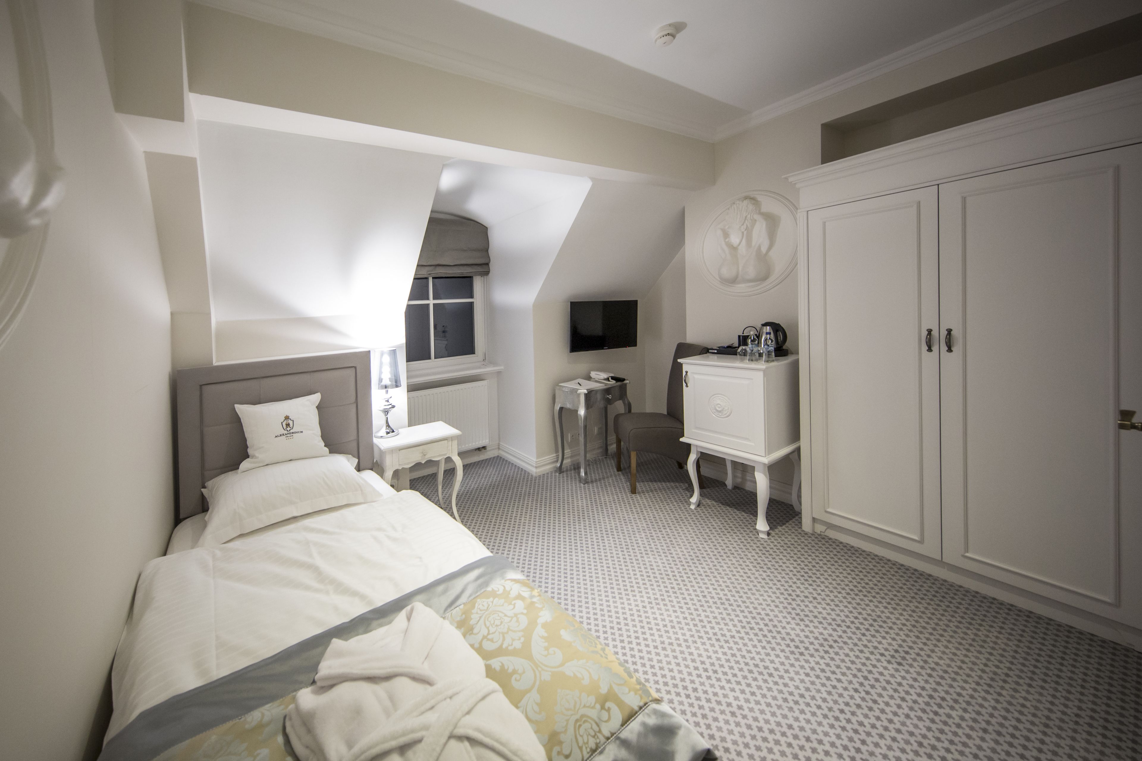 Una habitación de hotel con cama, escritorio, armario y televisor.