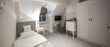 Una habitación de hotel con cama, escritorio, armario y televisor.
