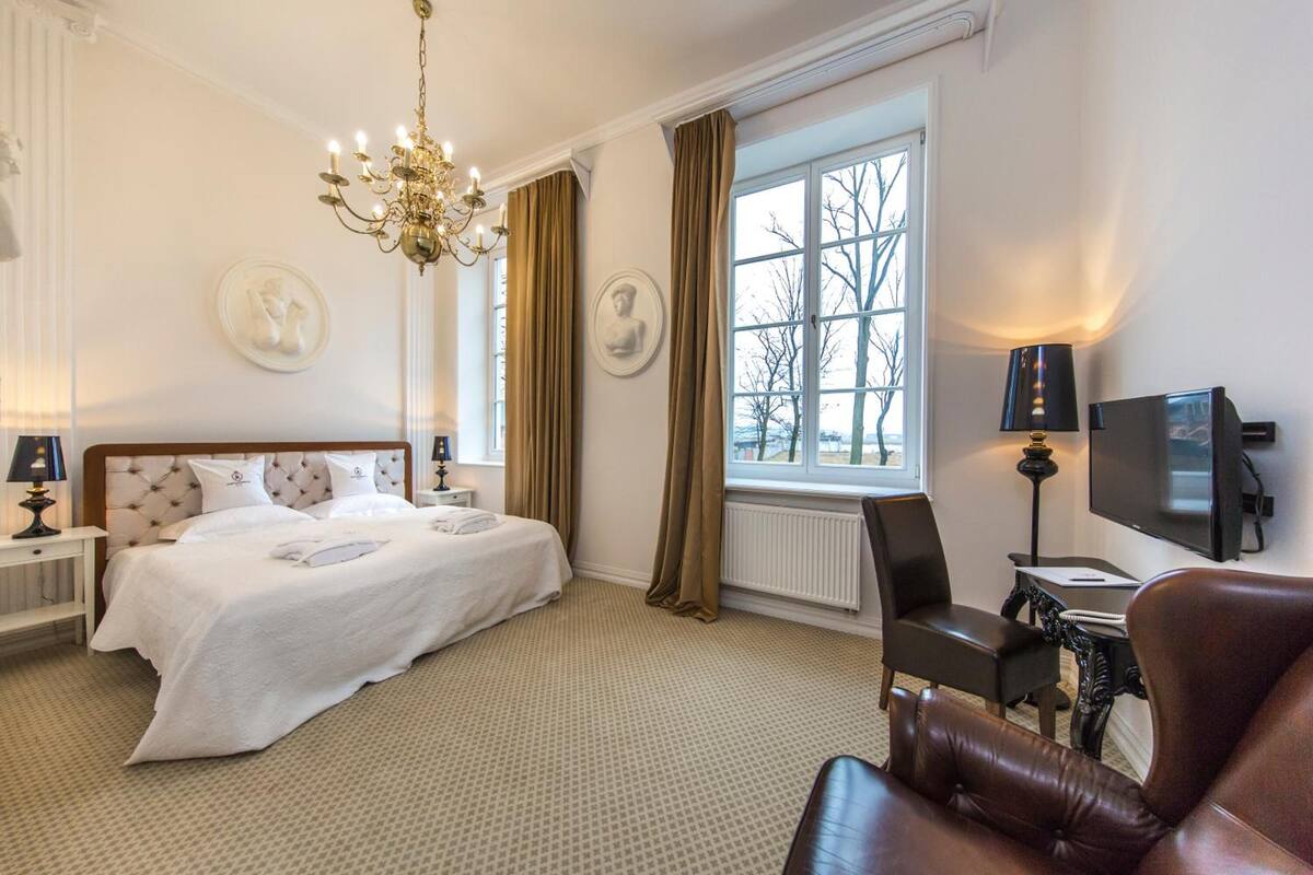 Une chambre d’hôtel avec un grand lit, une télévision, un bureau et une fenêtre avec des rideaux.