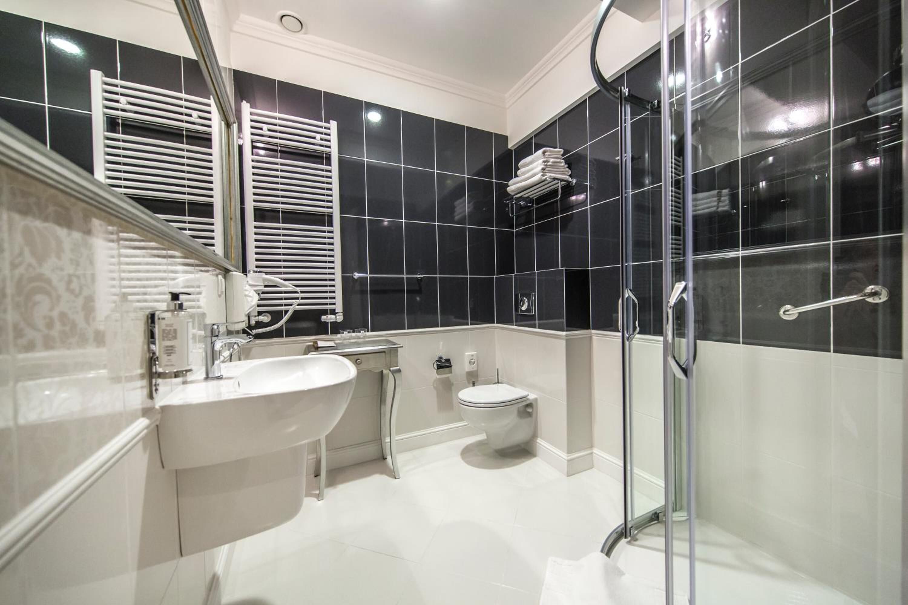 A modern bathroom with a white sink, toilet, and glass shower enclosure.