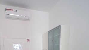 Une petite cuisine équipée avec une porte blanche, un évier encastré et une petite poubelle.